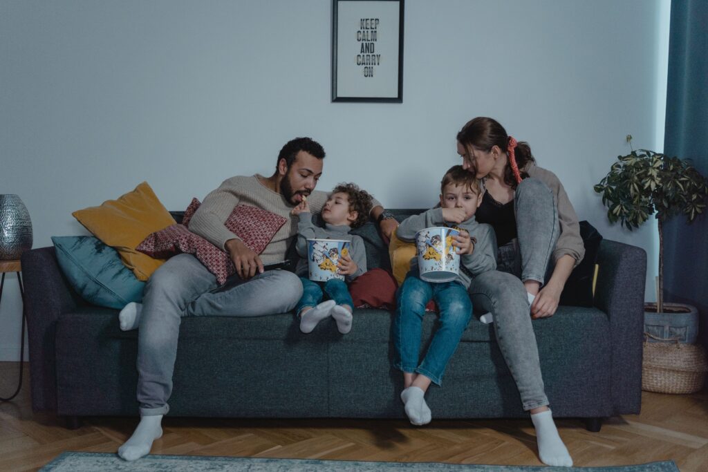 A family shares bonding time with popcorn on the sofa during movie night.